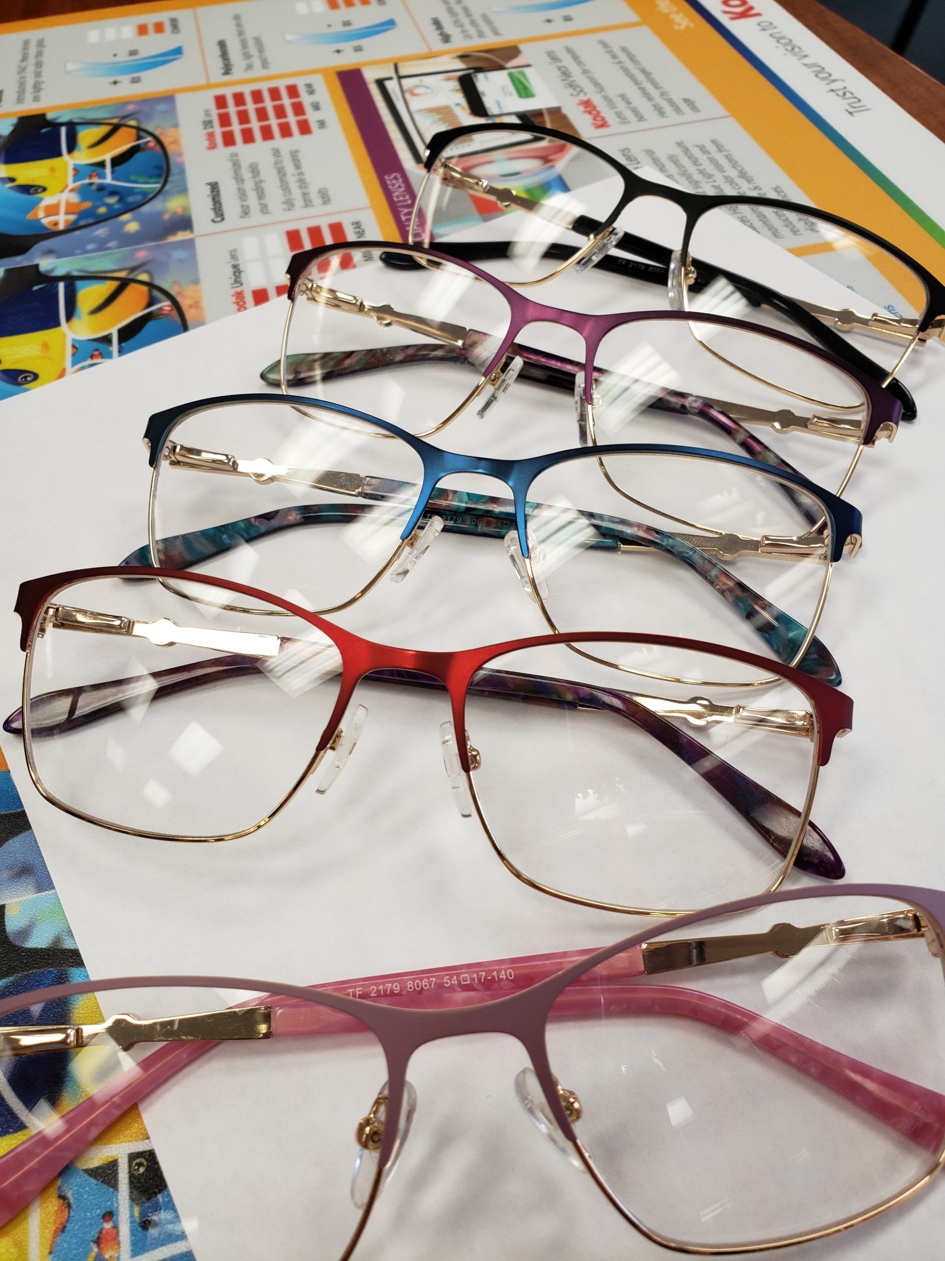 Multiple large frame glasses laid out on a row on a desk